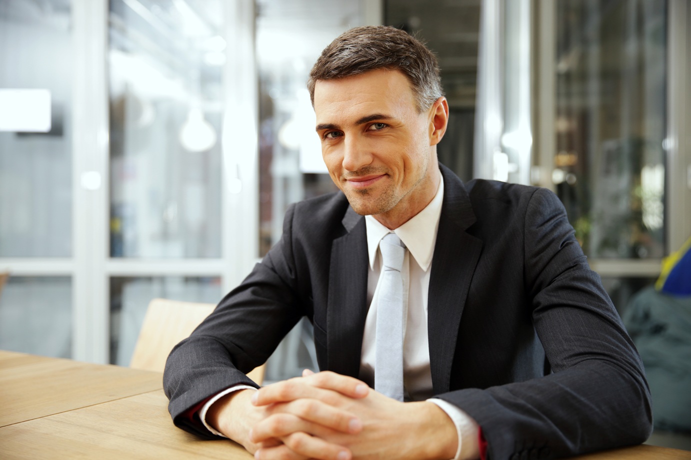 happy-businessman-sitting-at-the-table-in-office-CXCLT9V Happy Businessman Sitting At The Table In Office CXCLT9V